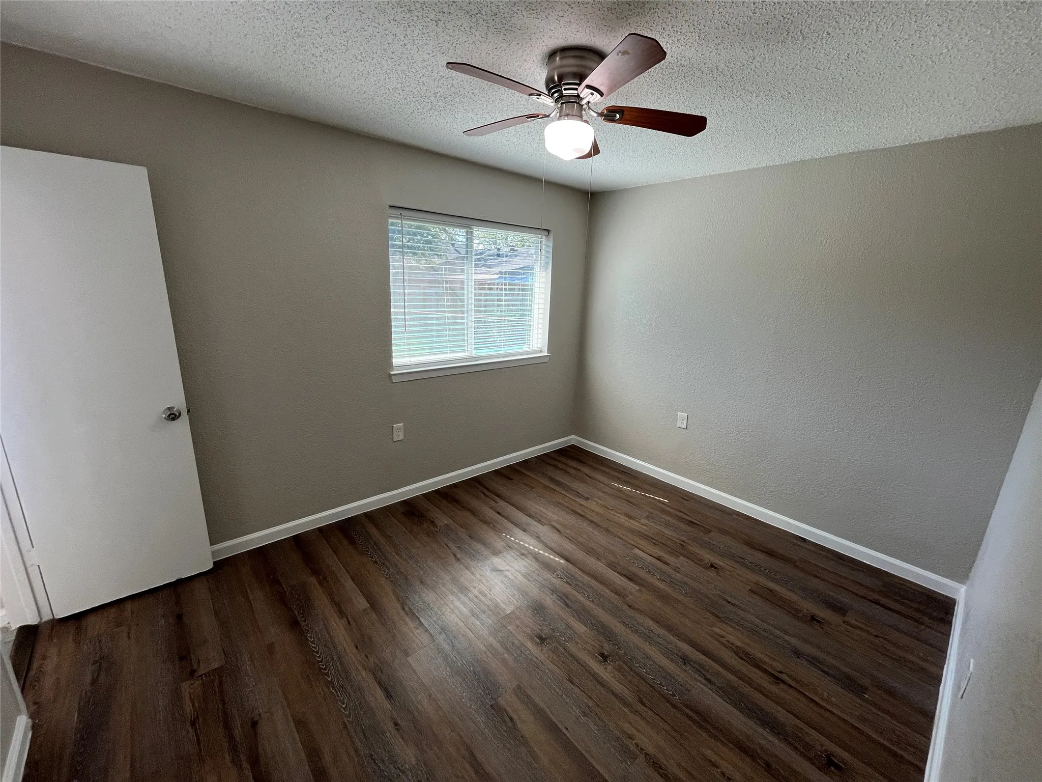 Wood-finish flooring with neutral wall tones and a ceiling fan with integrated lighting