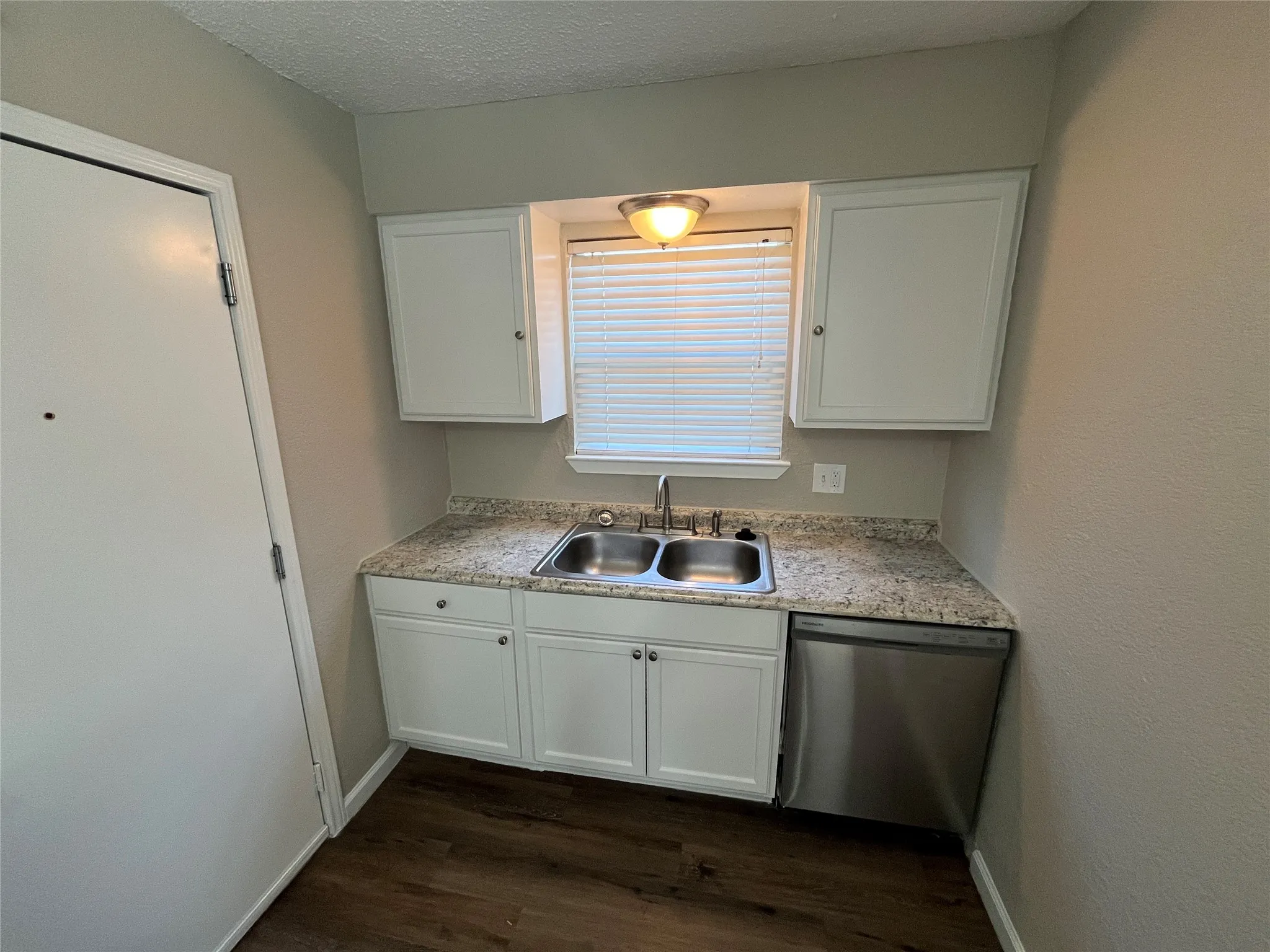 Dual stainless steel sink with a chrome faucet, white cabinetry, granite-finish countertop, and stainless steel dishwasher