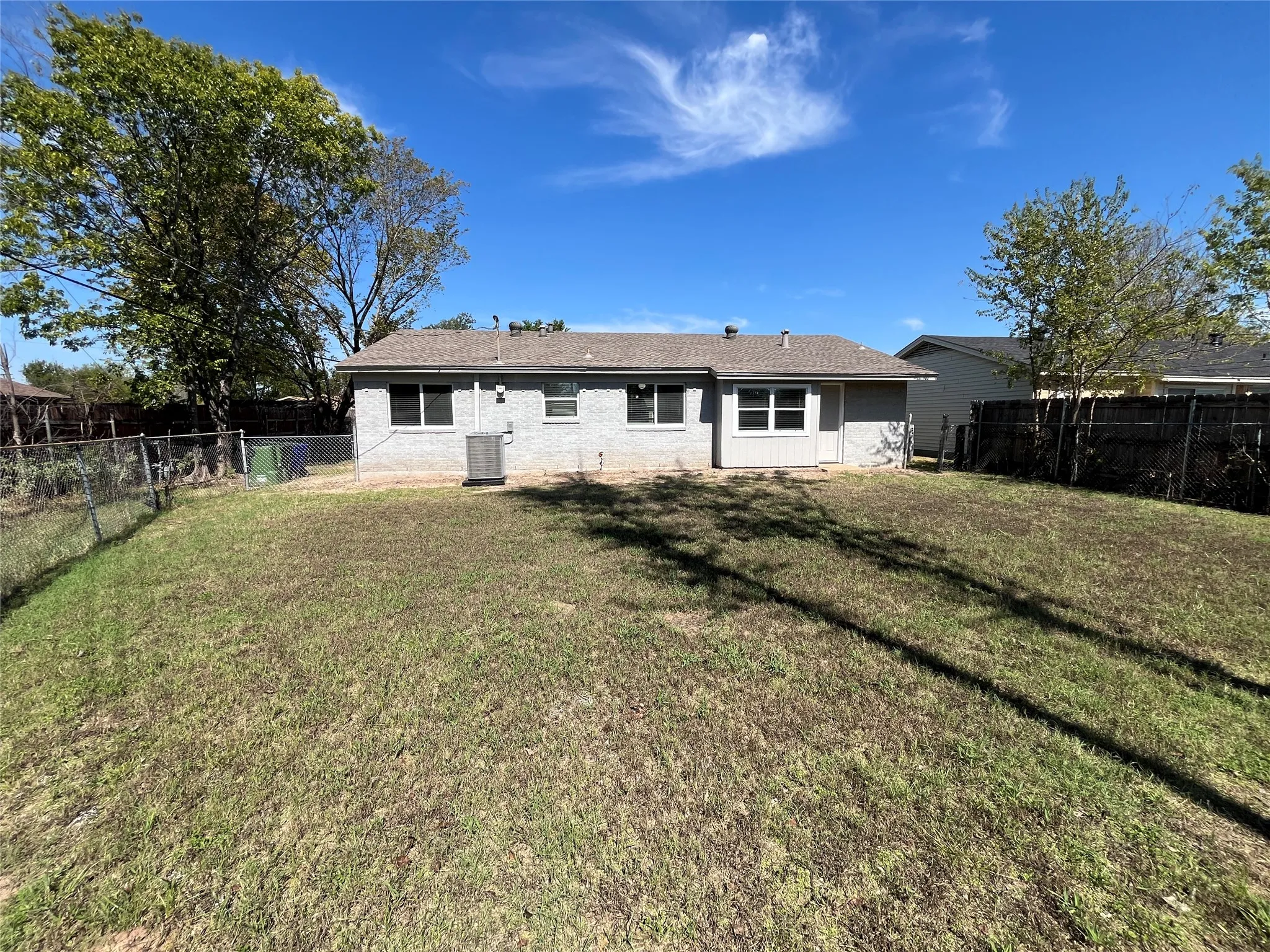 Expansive backyard featuring a chain link fence, a wood privacy fence, and mature trees