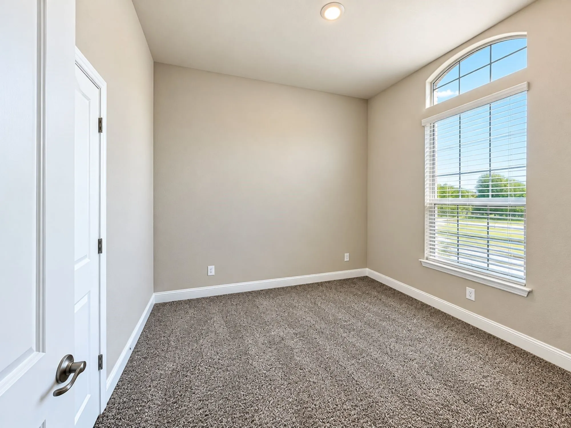 Arched window with blinds, recessed lighting, neutral wall paint, and textured carpet flooring
