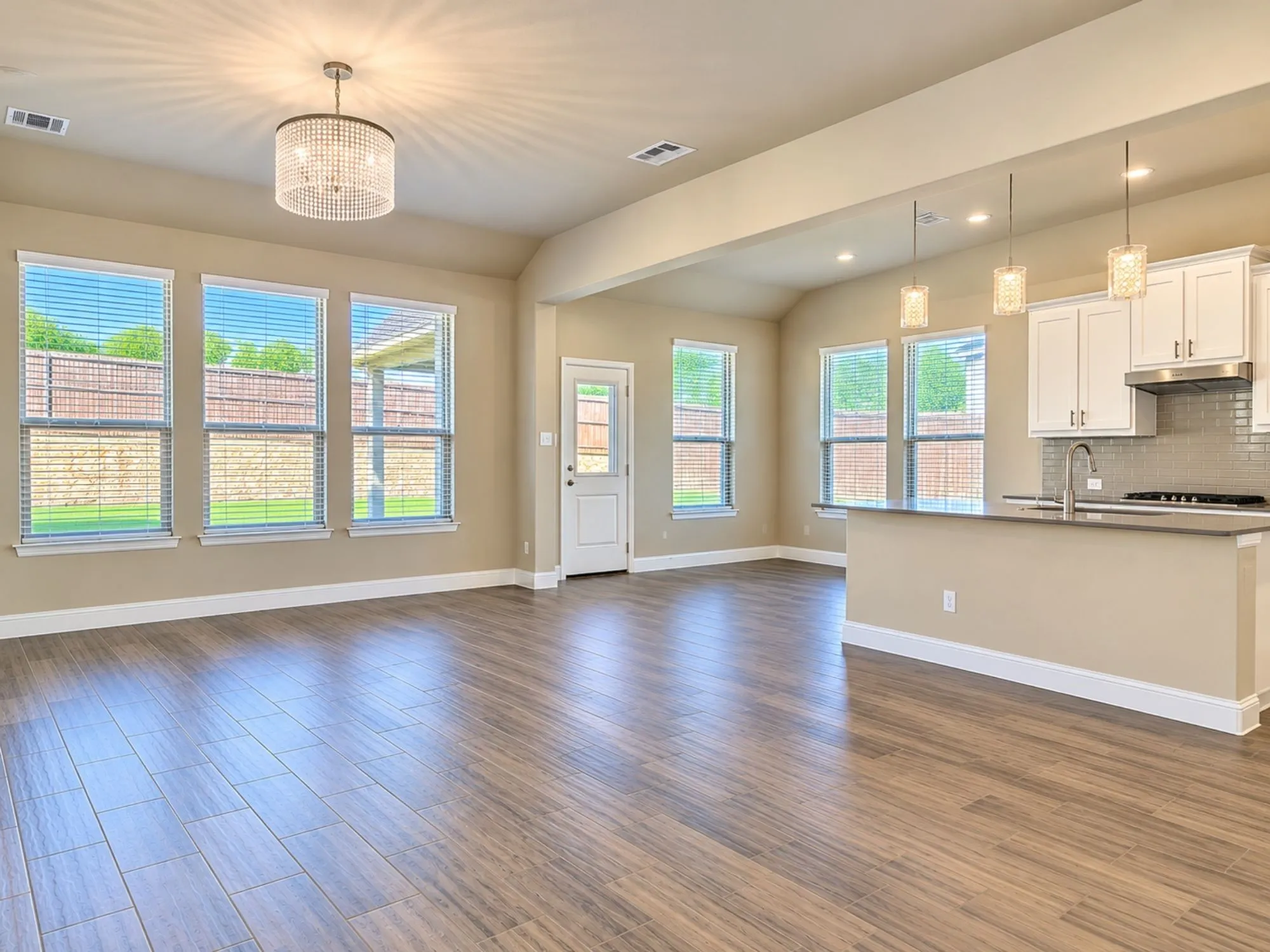 Expansive room with wood-finish flooring and a decorative chandelier