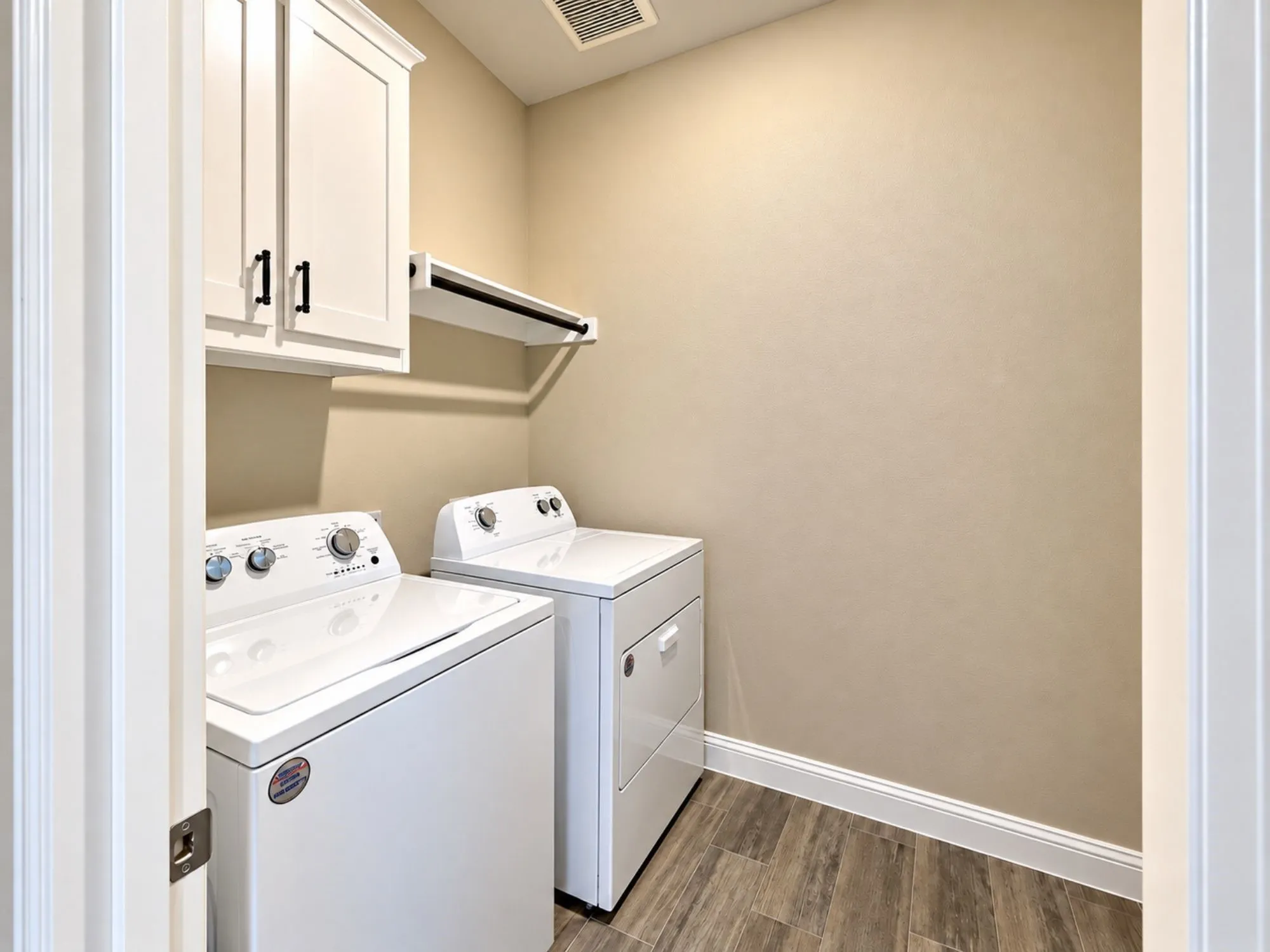 White shaker-style cabinetry with matte black hardware, wood-finish flooring, and a built-in hanging rod