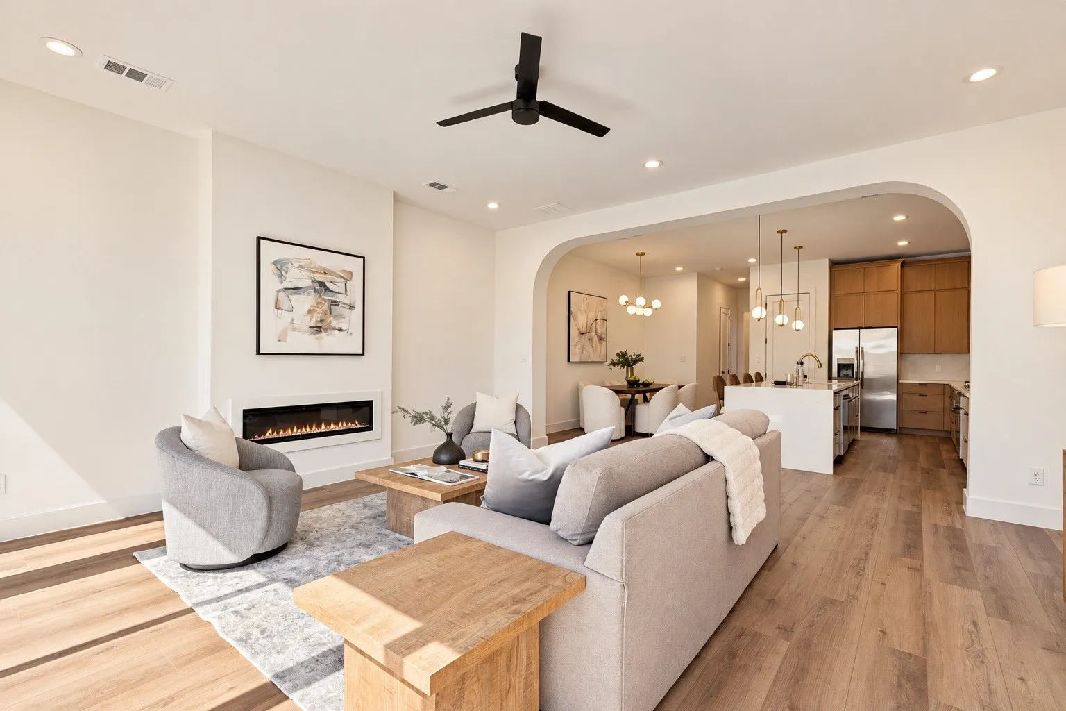 Recessed lighting, wood-finish flooring, a modern linear fireplace, a ceiling fan, and an arched entryway