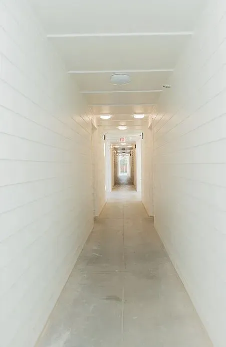Long hallway featuring light-colored shiplap walls, a concrete floor, and recessed ceiling lighting