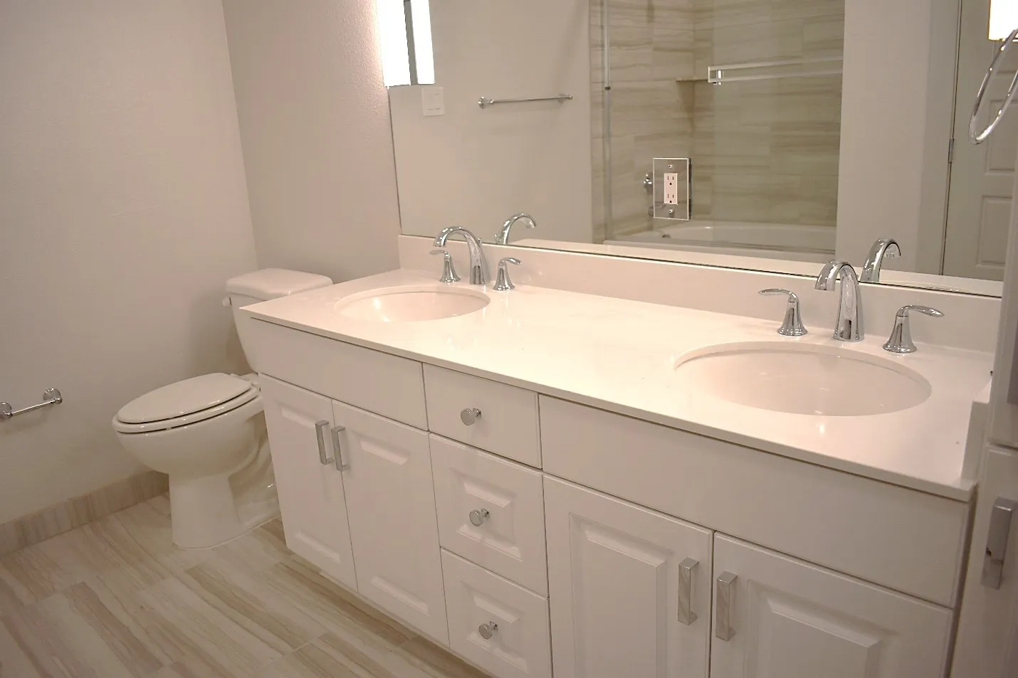Dual vanity with light-toned countertop, integrated sinks, and polished chrome fixtures