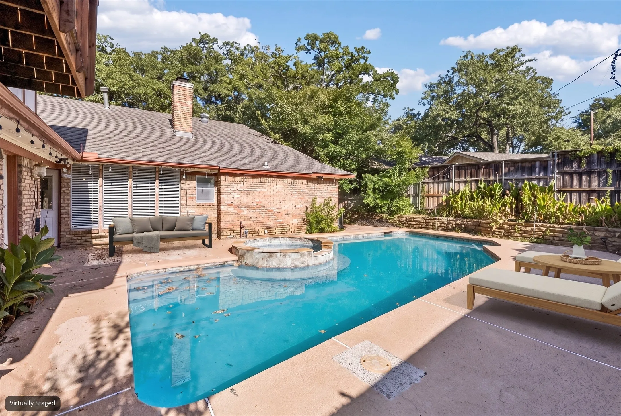 Inviting backyard pool surrounded by mature trees and patio space.