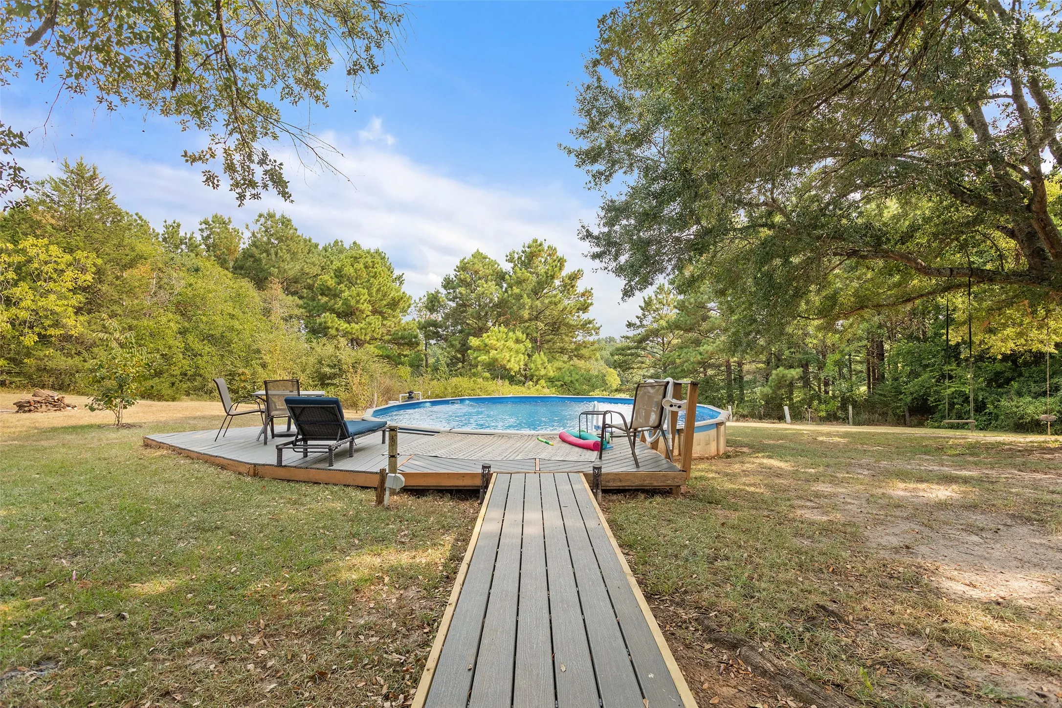 Above-ground pool with surrounding wood-finish deck and composite walkway