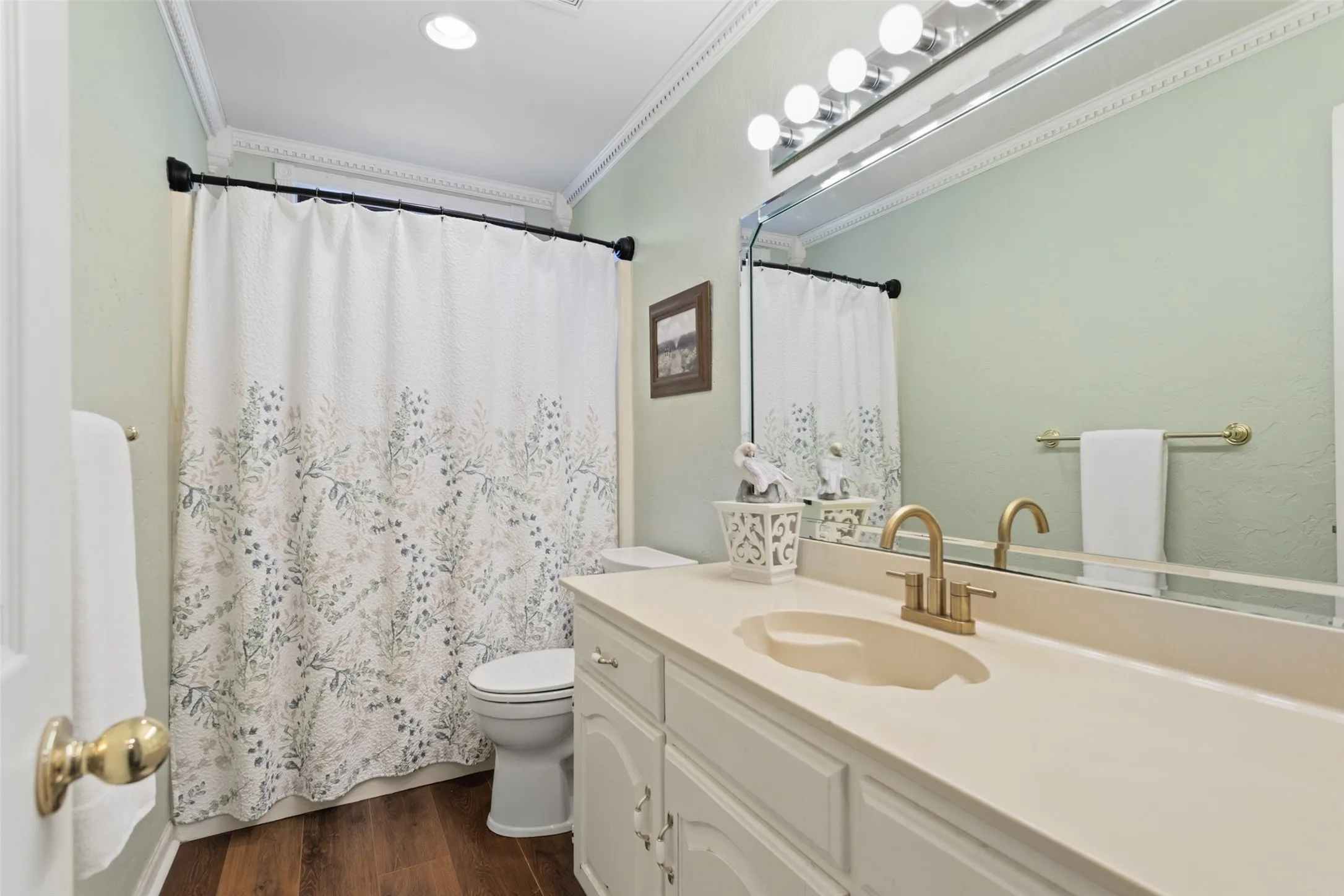 White vanity with a neutral-toned countertop and an integrated sink, featuring a gold-finish faucet