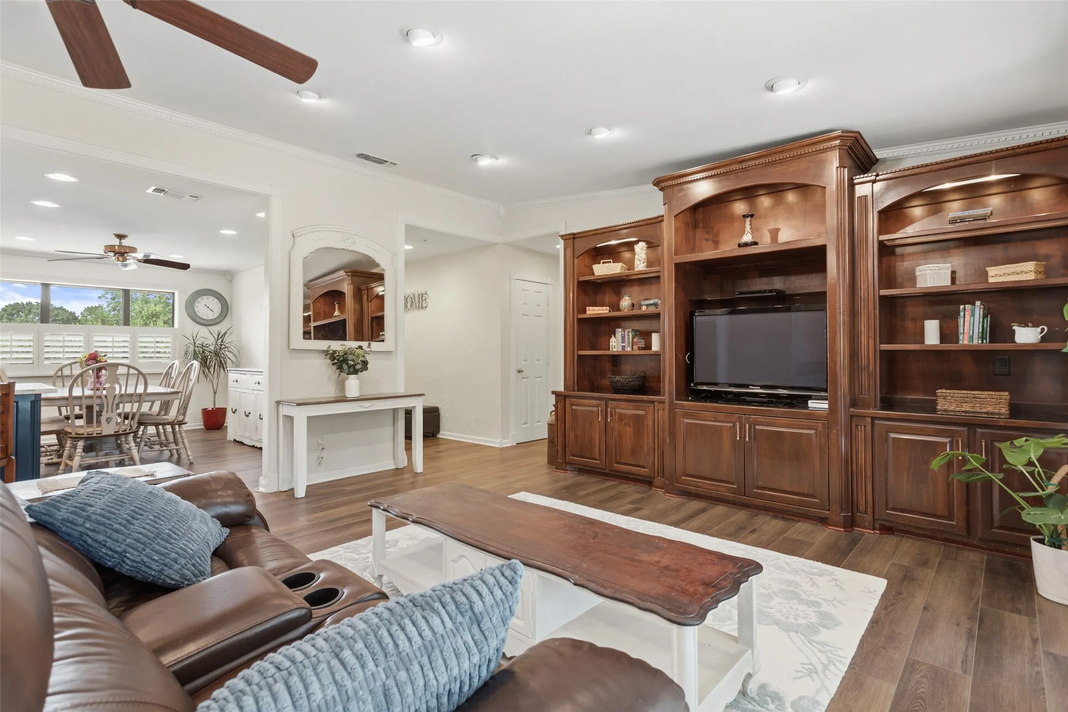 Built-in media center with shelving, wood-finish flooring, recessed lighting, and ceiling fan