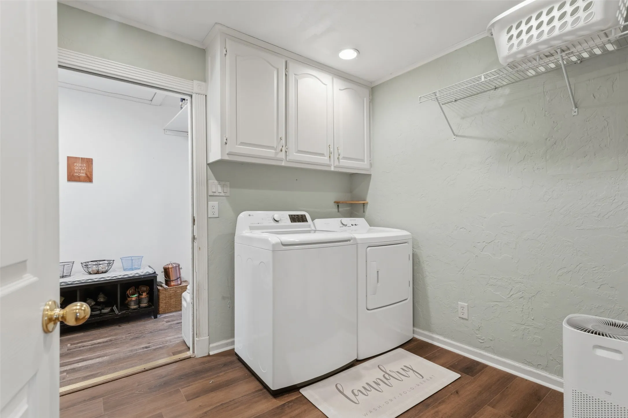 White upper cabinetry, wood-finish flooring, and a wire storage shelf