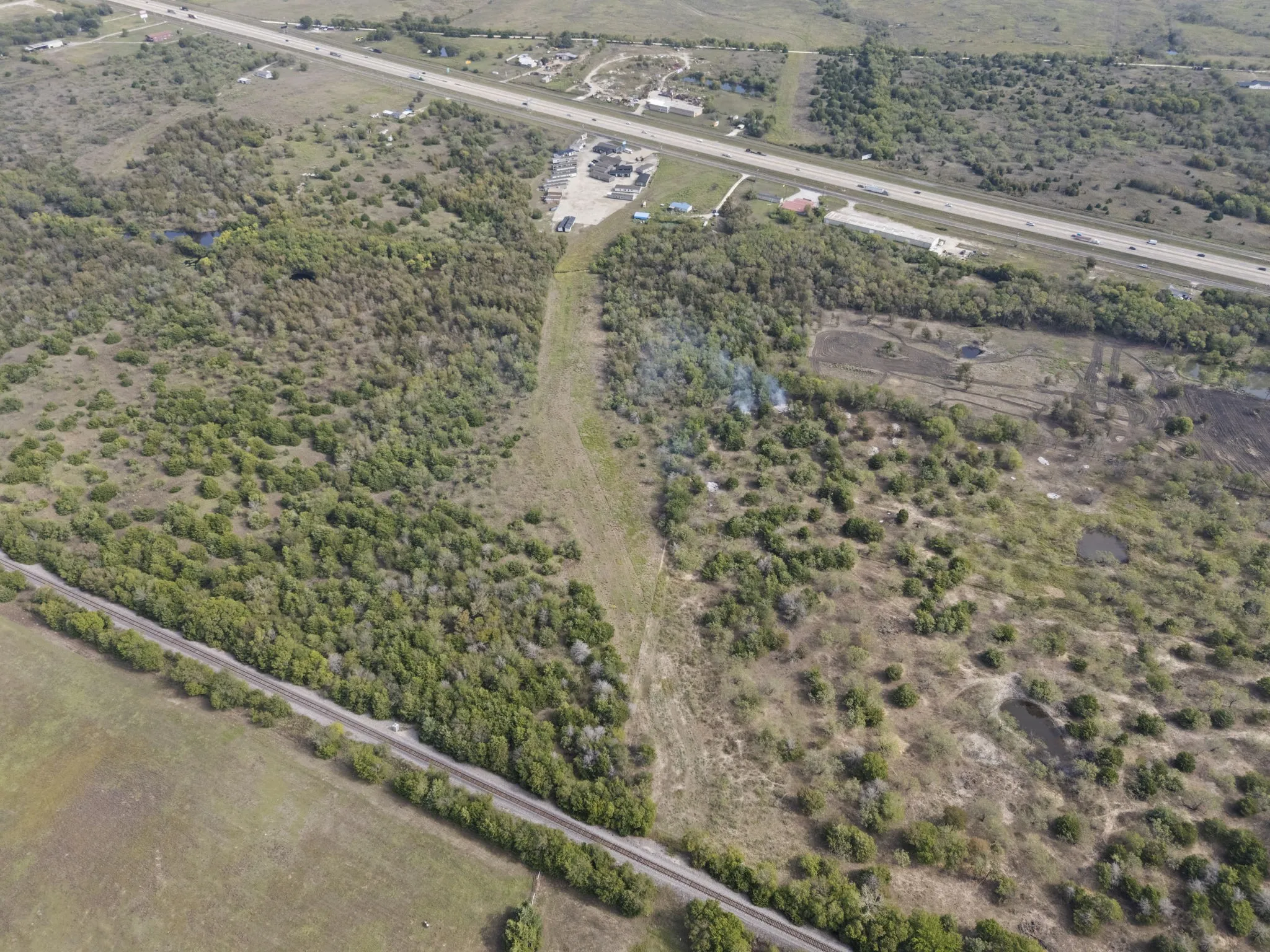 Expansive undeveloped land featuring natural foliage and a visible roadway