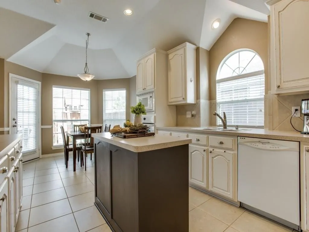 Kitchen featuring a central island, tile flooring, vaulted ceiling, and recessed lighting