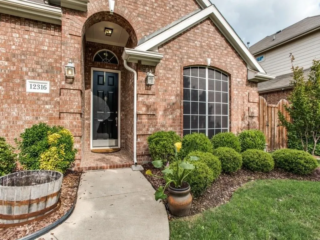 Brick facade with an arched entry, a dark paneled front door, and an arched window