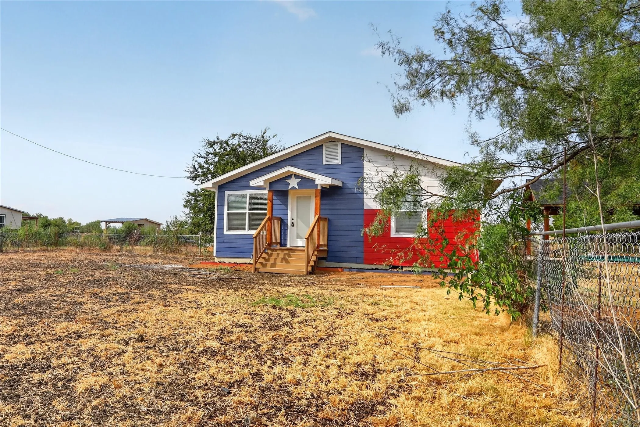 Vibrant exterior with blue and red siding, white trim, and a prominent front porch with wood railings