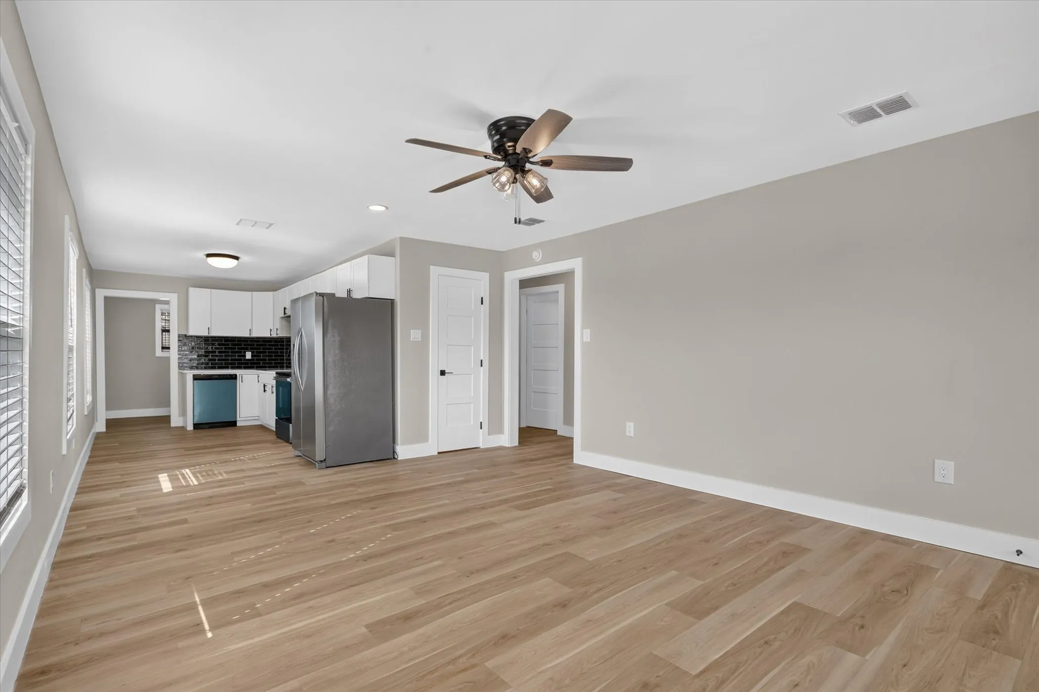 Wood-finish flooring, recessed lighting, ceiling fan, white cabinetry, and a black subway tile backsplash