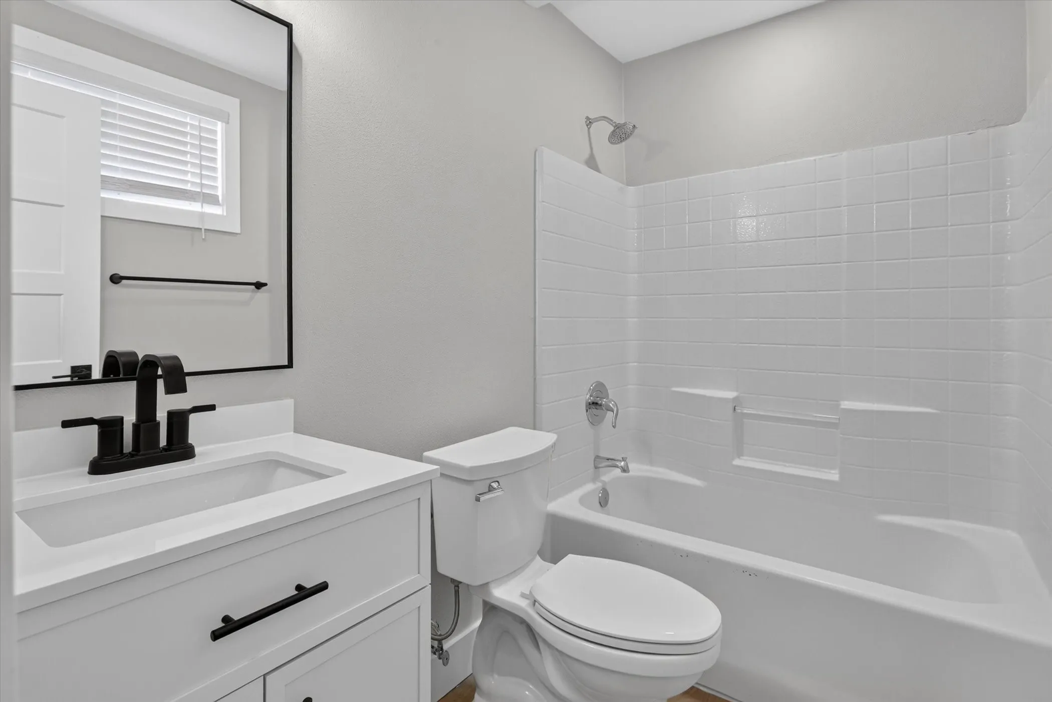 White vanity with black hardware, rectangular undermount sink, black matte faucet, and a rectangular mirror