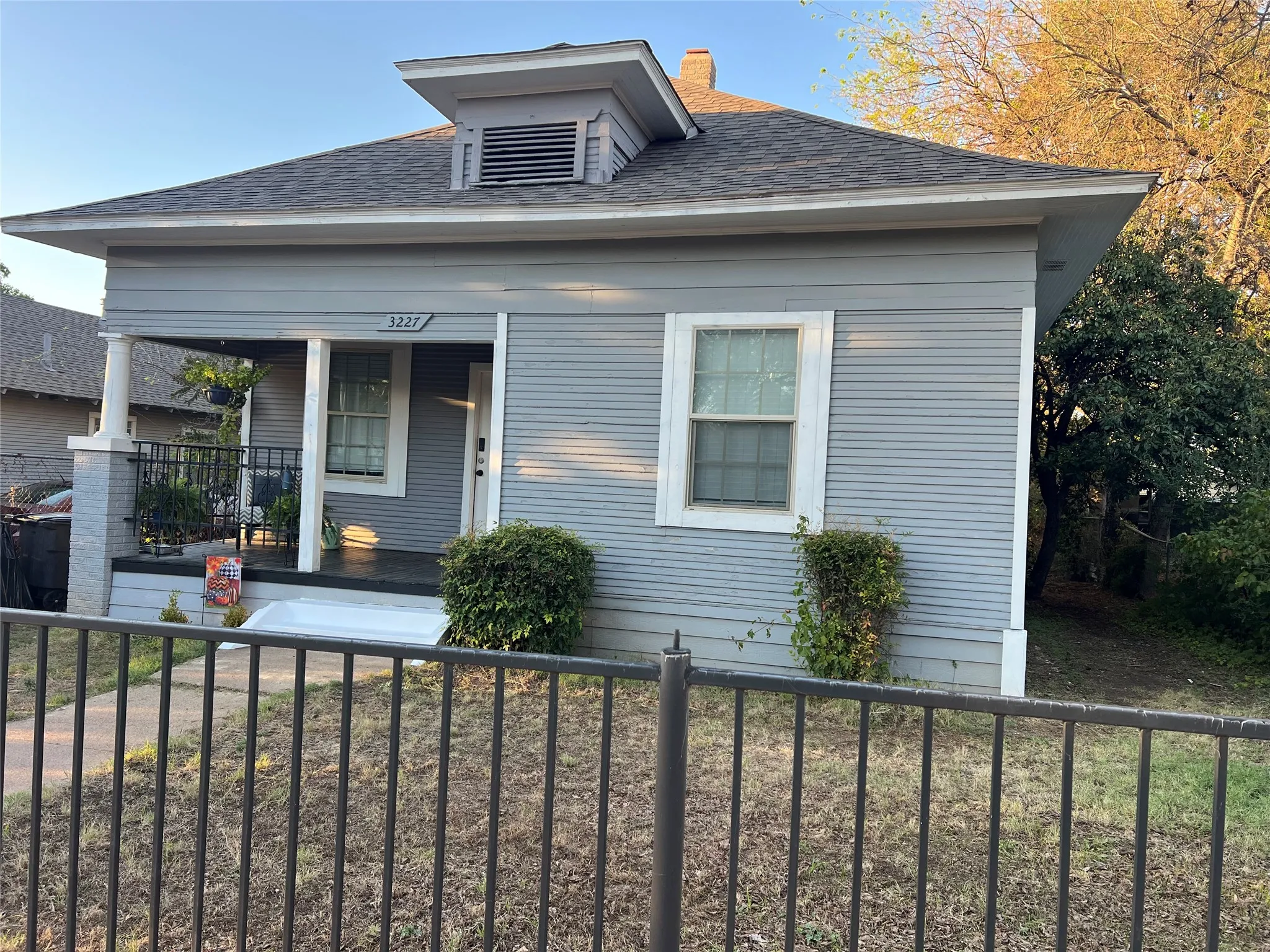 Front porch with a black metal railing and grey painted wood siding