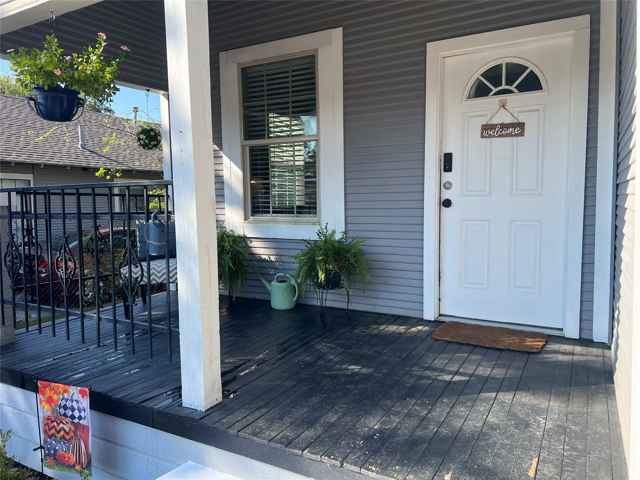 Covered front porch featuring gray horizontal siding and black wood-finish flooring