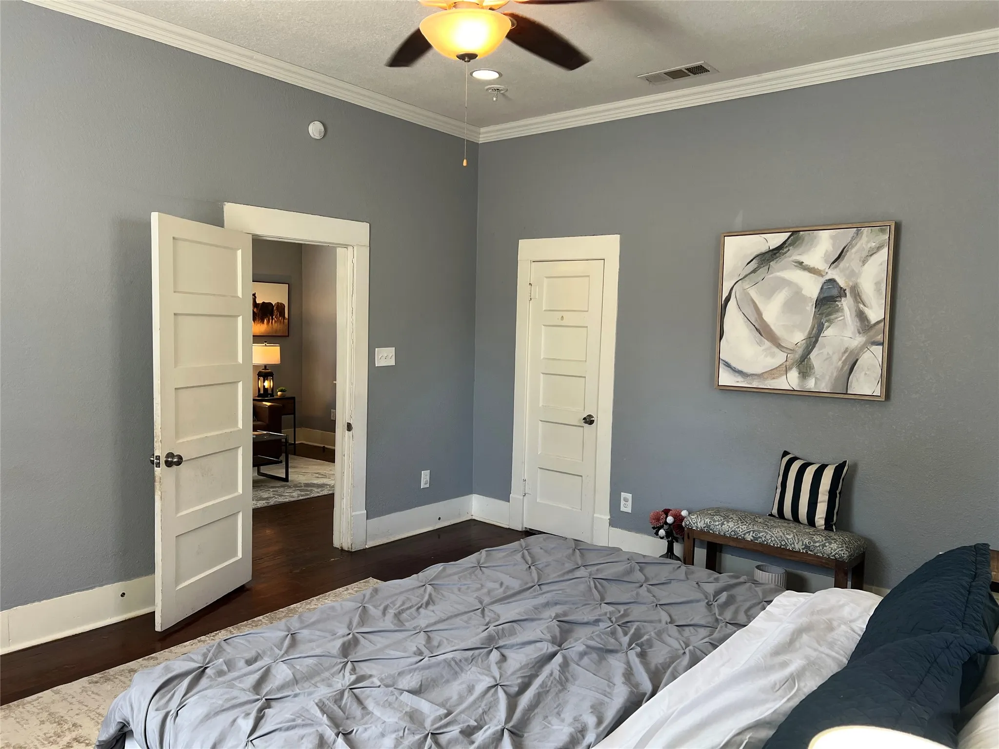 Crown molding, ceiling fan, wood-finish flooring, paneled interior doors, and neutral wall tones