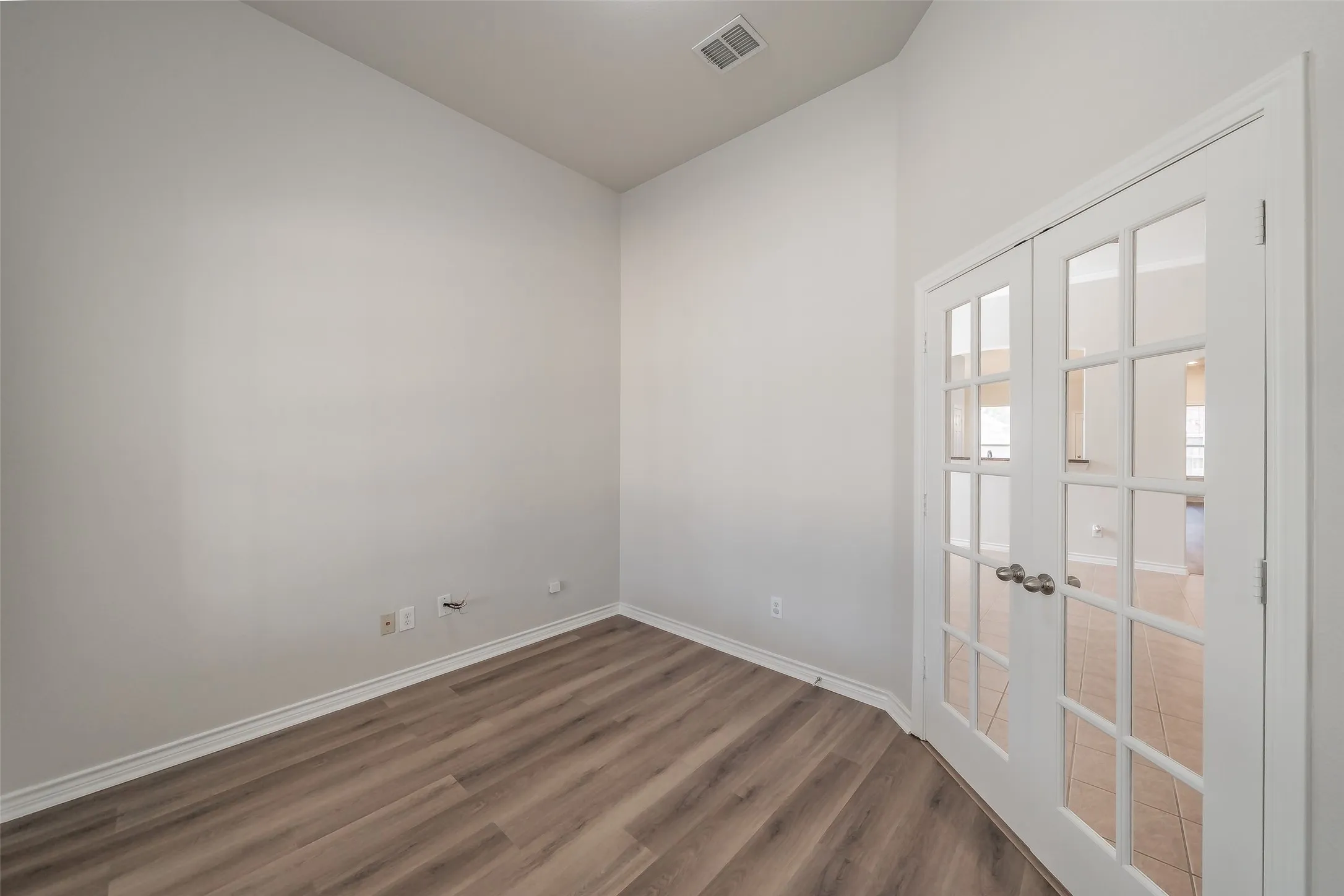 Wood-finish flooring with white baseboards, white walls, and a vaulted ceiling