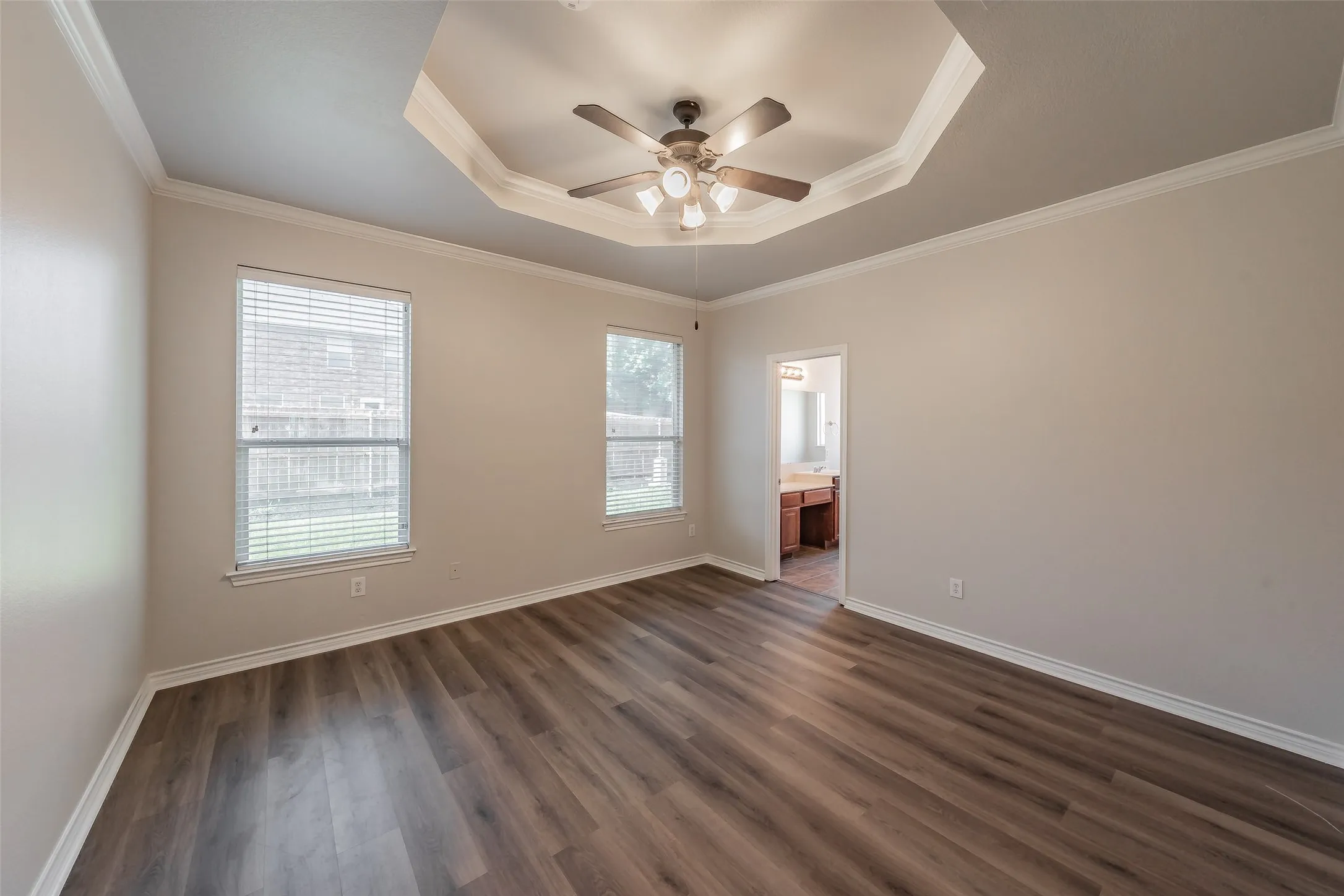 Spacious bedroom with recessed ceiling detail and integrated ceiling fan with lighting