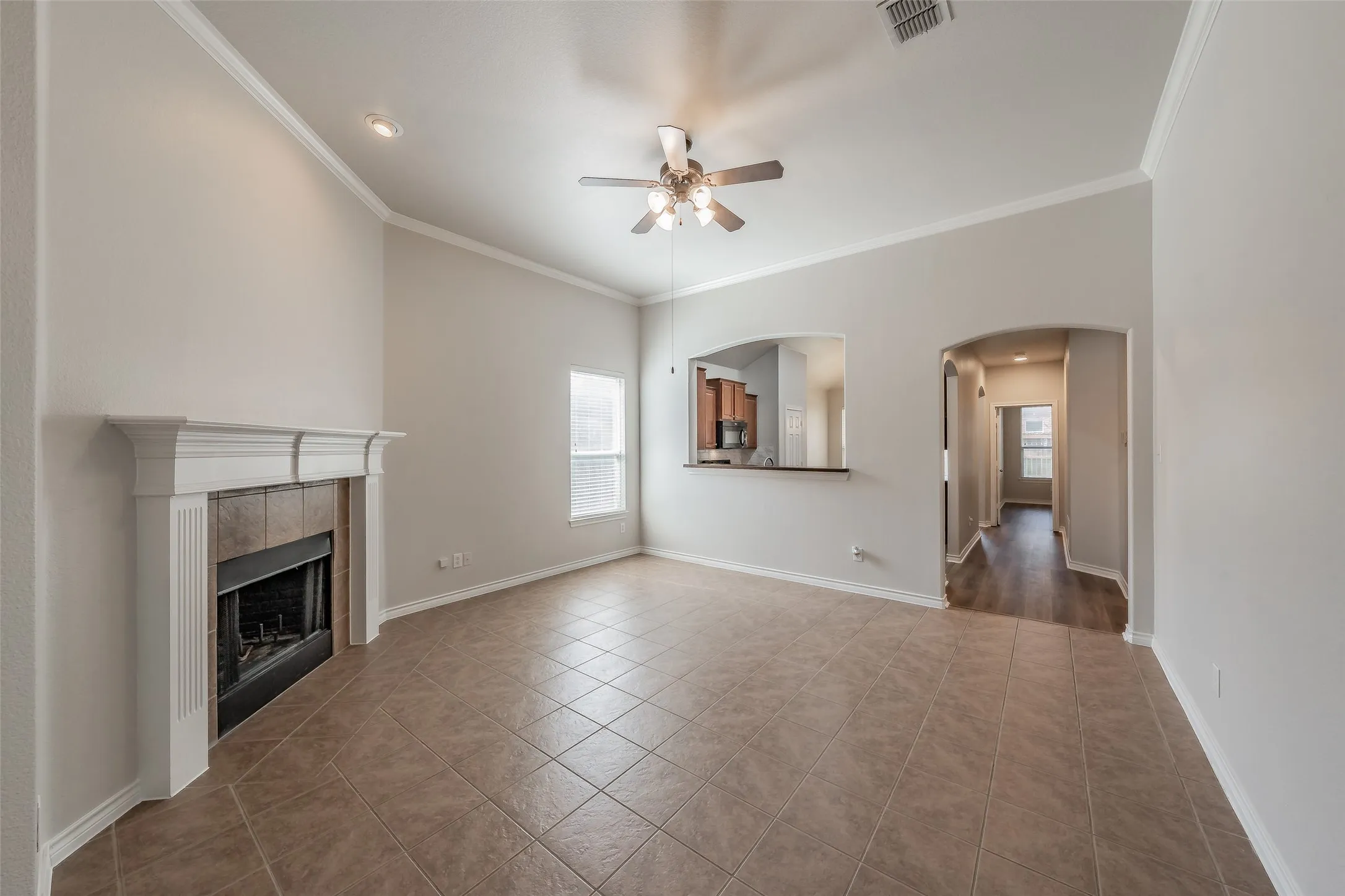Vaulted ceiling with crown molding, tile flooring, and a fireplace with a mantel