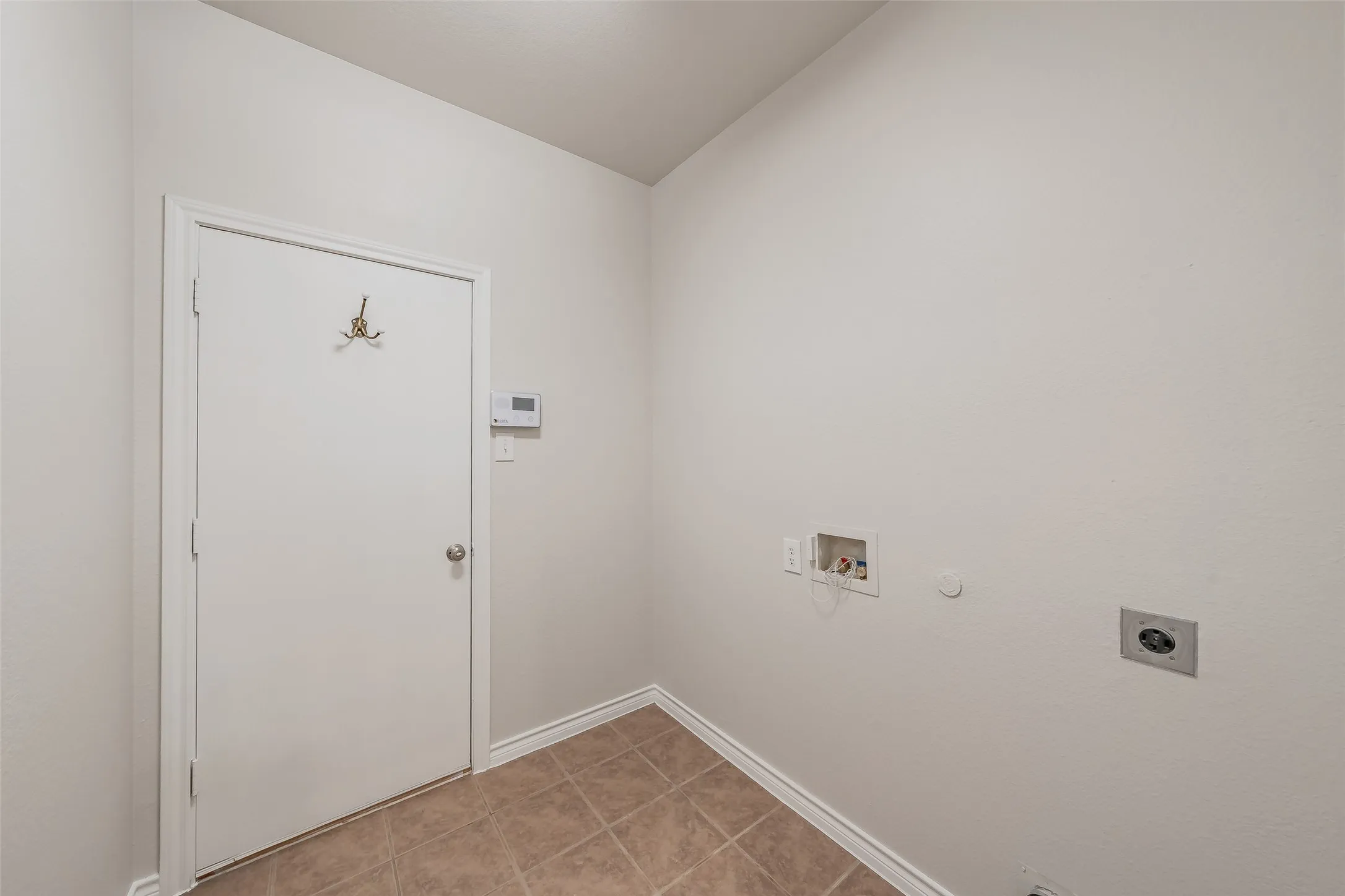 Utility area with a white door, tile flooring, and appliance hookups