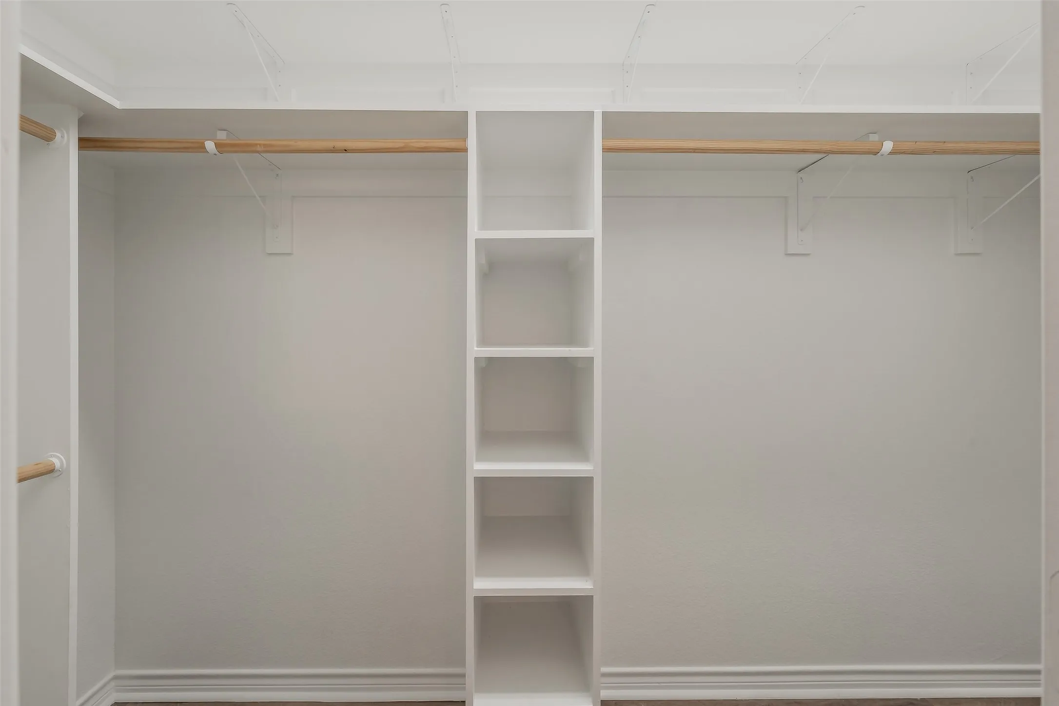 White built-in shelving with multiple cubbies, wood-finish flooring, and white walls