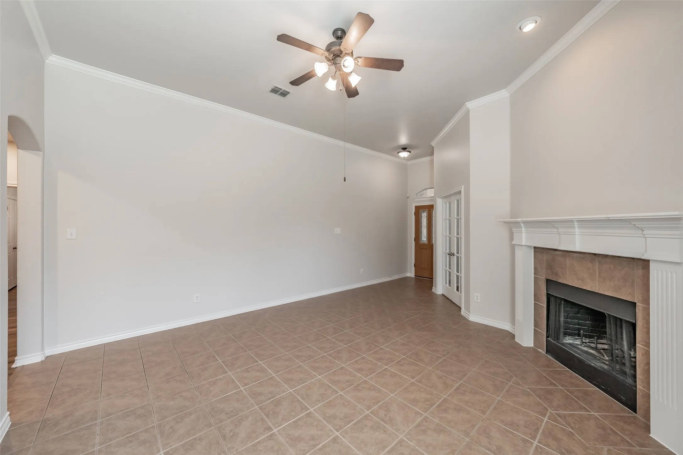 Tile flooring, crown molding, ceiling fan, recessed lighting, and a fireplace with a white mantel