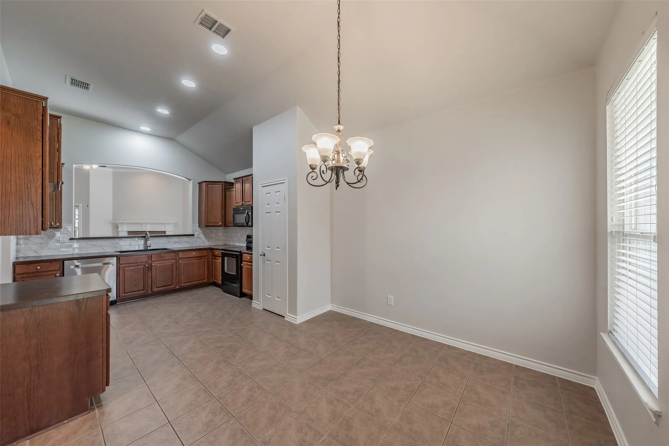 Kitchen featuring wood cabinetry, stainless steel appliances, tile flooring, and a pass-through window