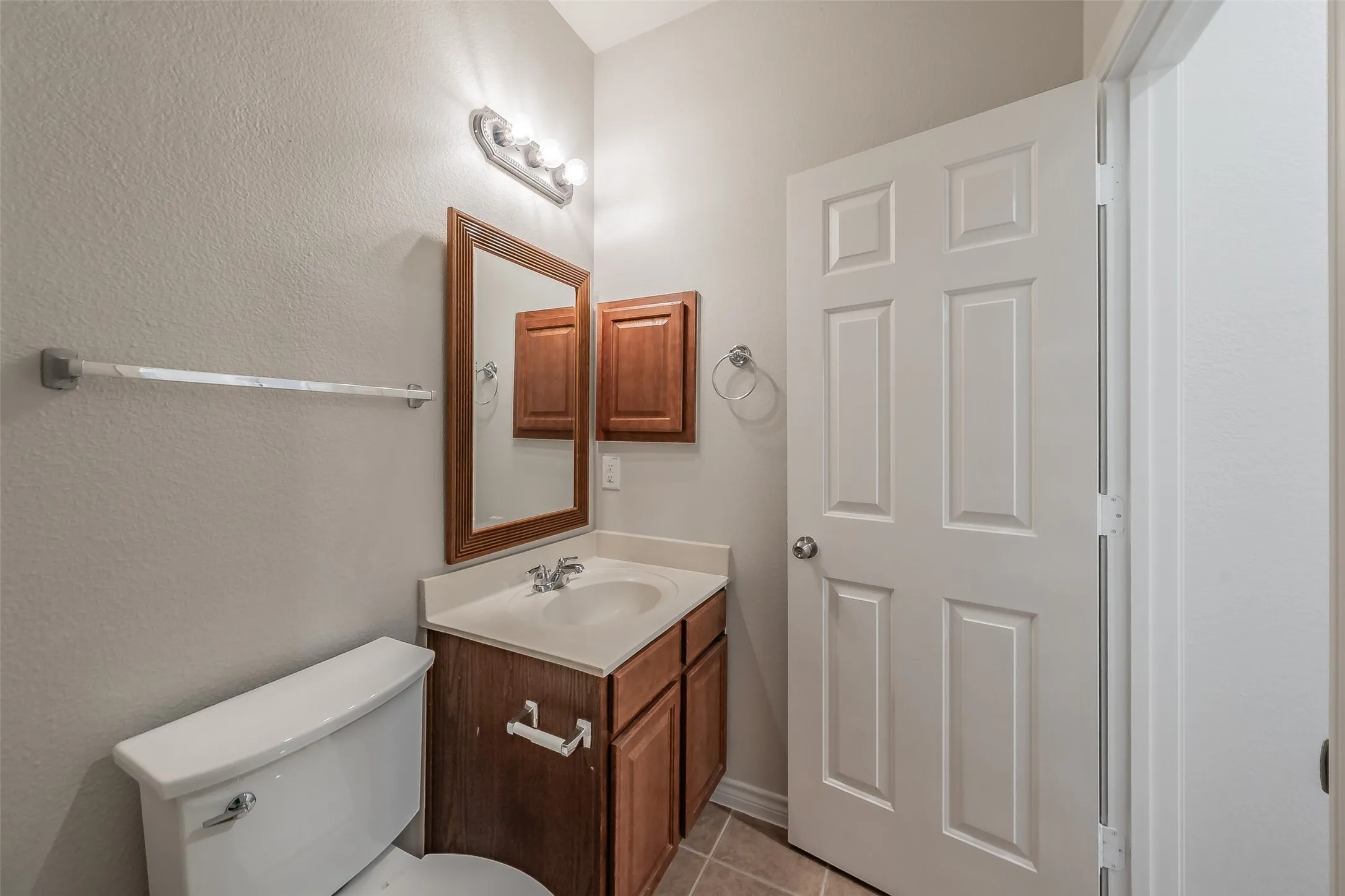 Vanity with wood-finish cabinetry, integrated sink, and wall-mounted mirror