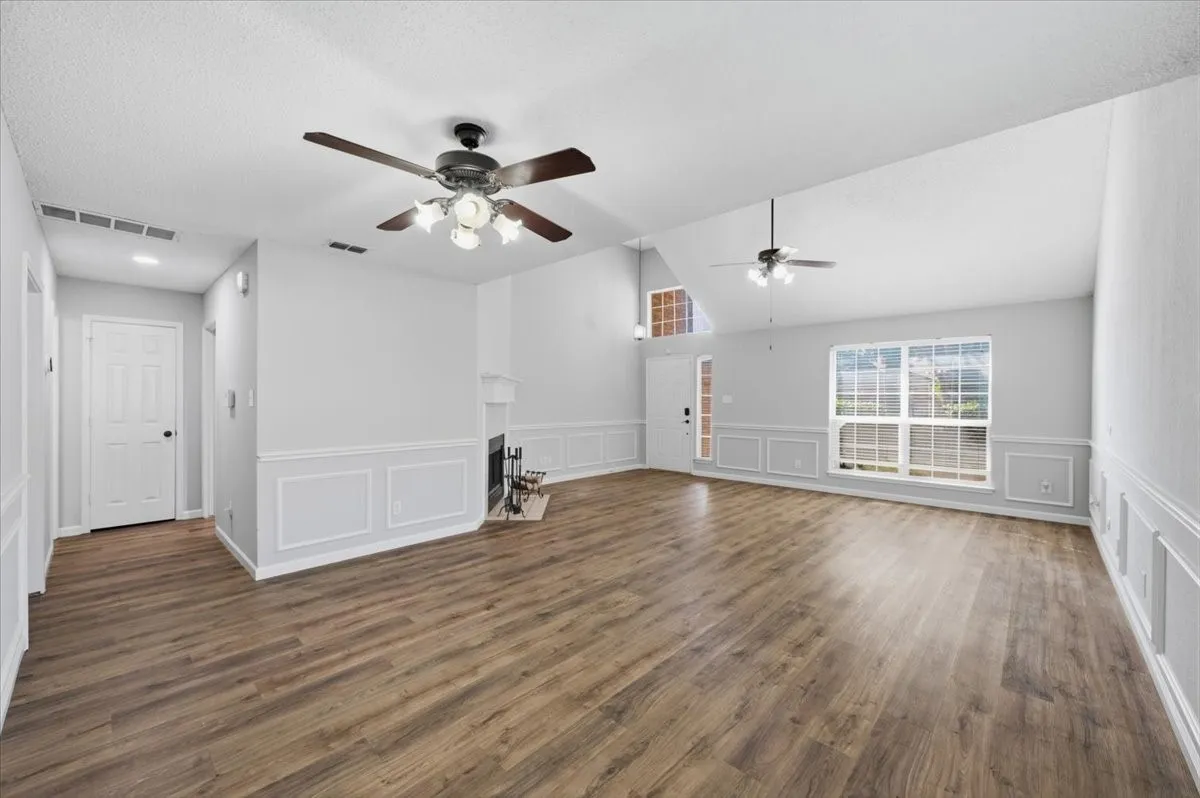 Vaulted ceilings, wood-finish flooring, wainscoting, fireplace with mantel, and ceiling fans