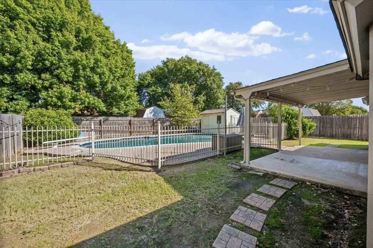 Backyard featuring a covered patio, concrete slab, and a swimming pool with a surrounding fence