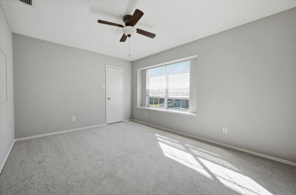 Light grey carpeting, neutral wall color, and a ceiling fan with light