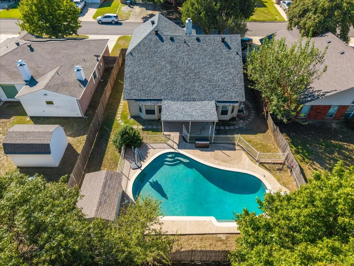 Fenced backyard featuring an in-ground swimming pool, covered patio, and a utility shed