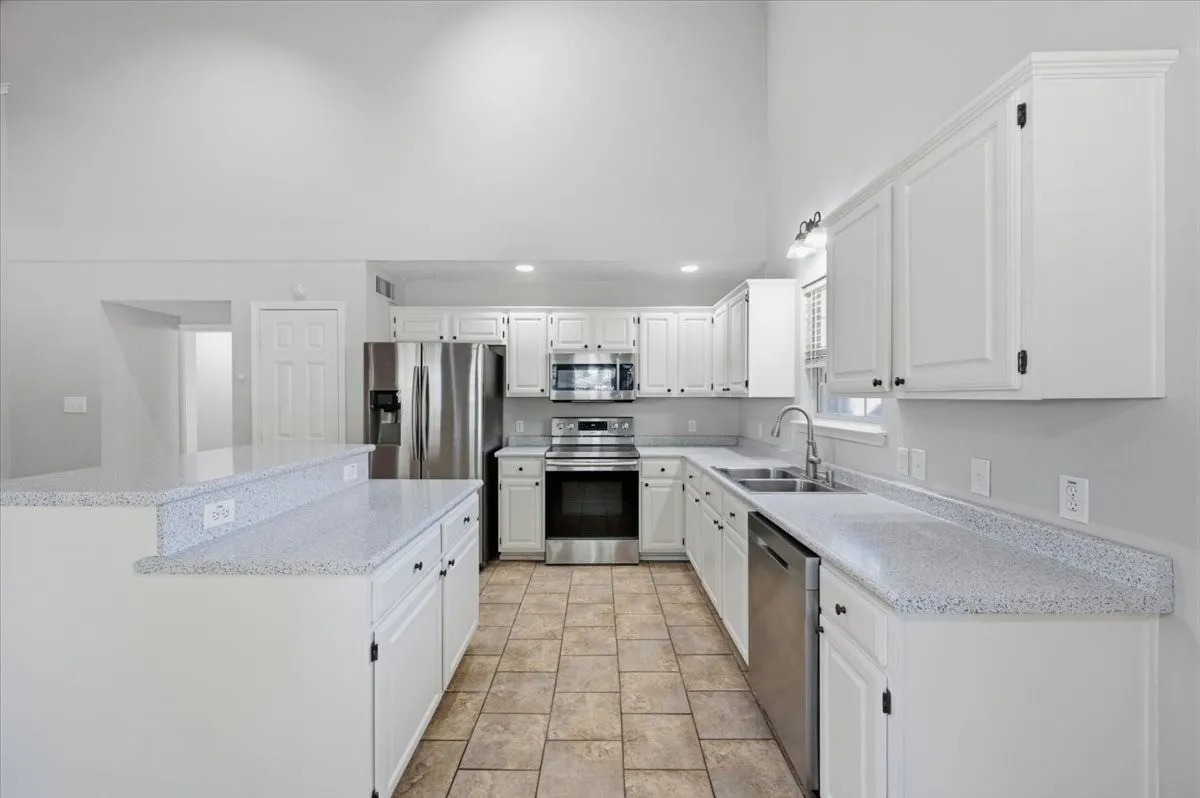 Kitchen featuring white cabinetry, light-toned countertops, stainless steel appliances, and tile flooring