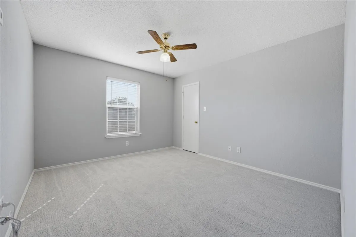 Vaulted ceiling, ceiling fan, neutral wall paint, white window blinds, and light-toned carpet