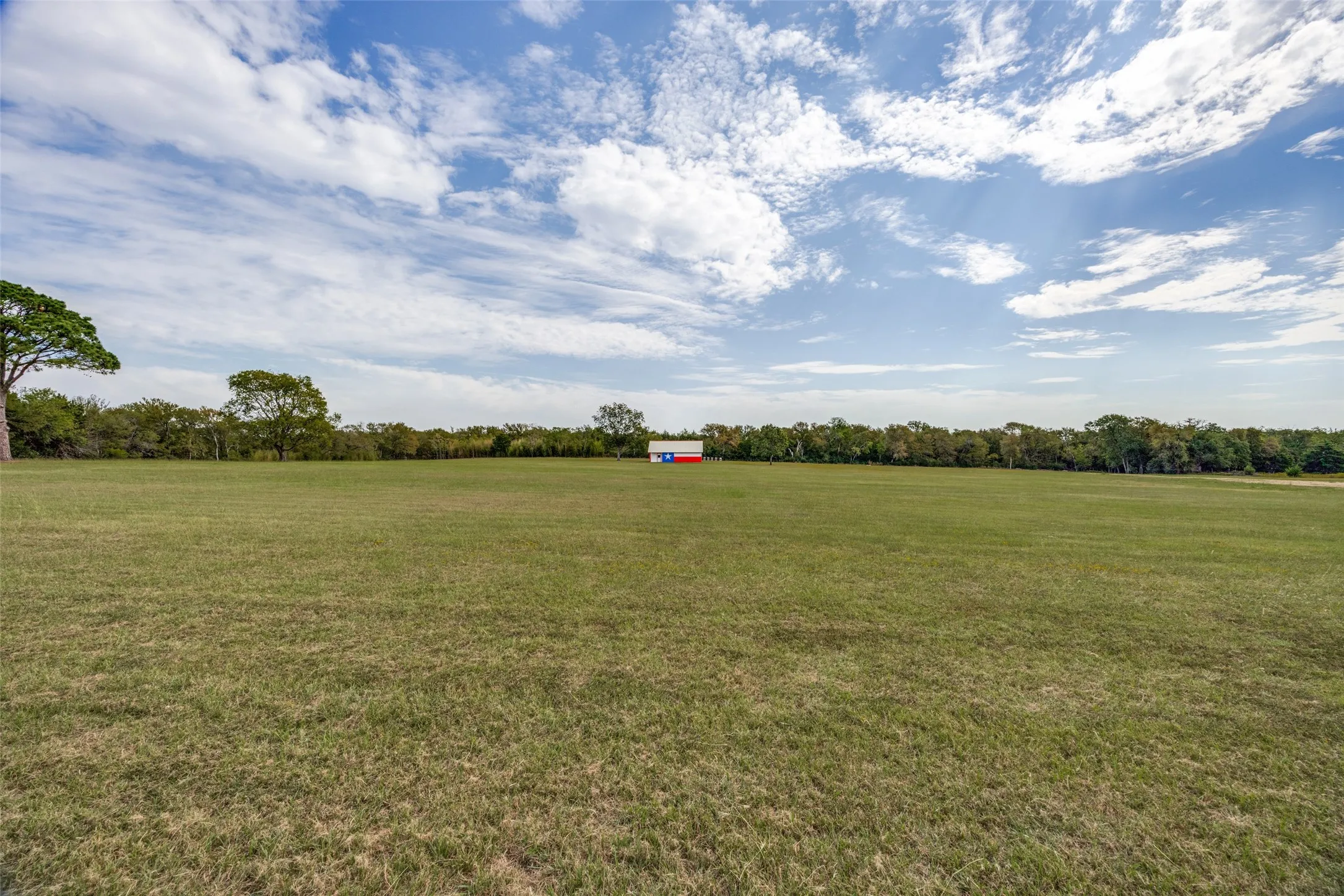 Expansive green field with a distant red and white structure