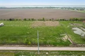 Expansive green space featuring a natural pond, a distant cultivated field, and a clear horizon