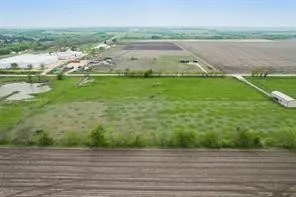 Expansive agricultural land featuring a large open field, a small pond, and a detached outbuilding