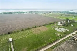 Expansive property featuring a cultivated field, natural water feature, and distant water scenery