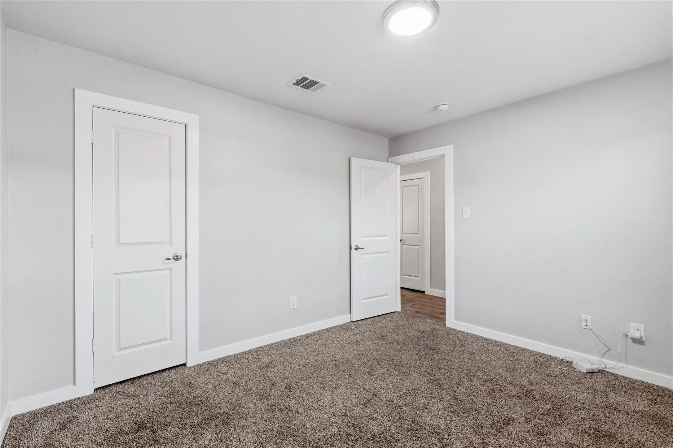Neutral wall color with a contrasting white trim, carpeted flooring, and a flush-mount ceiling light