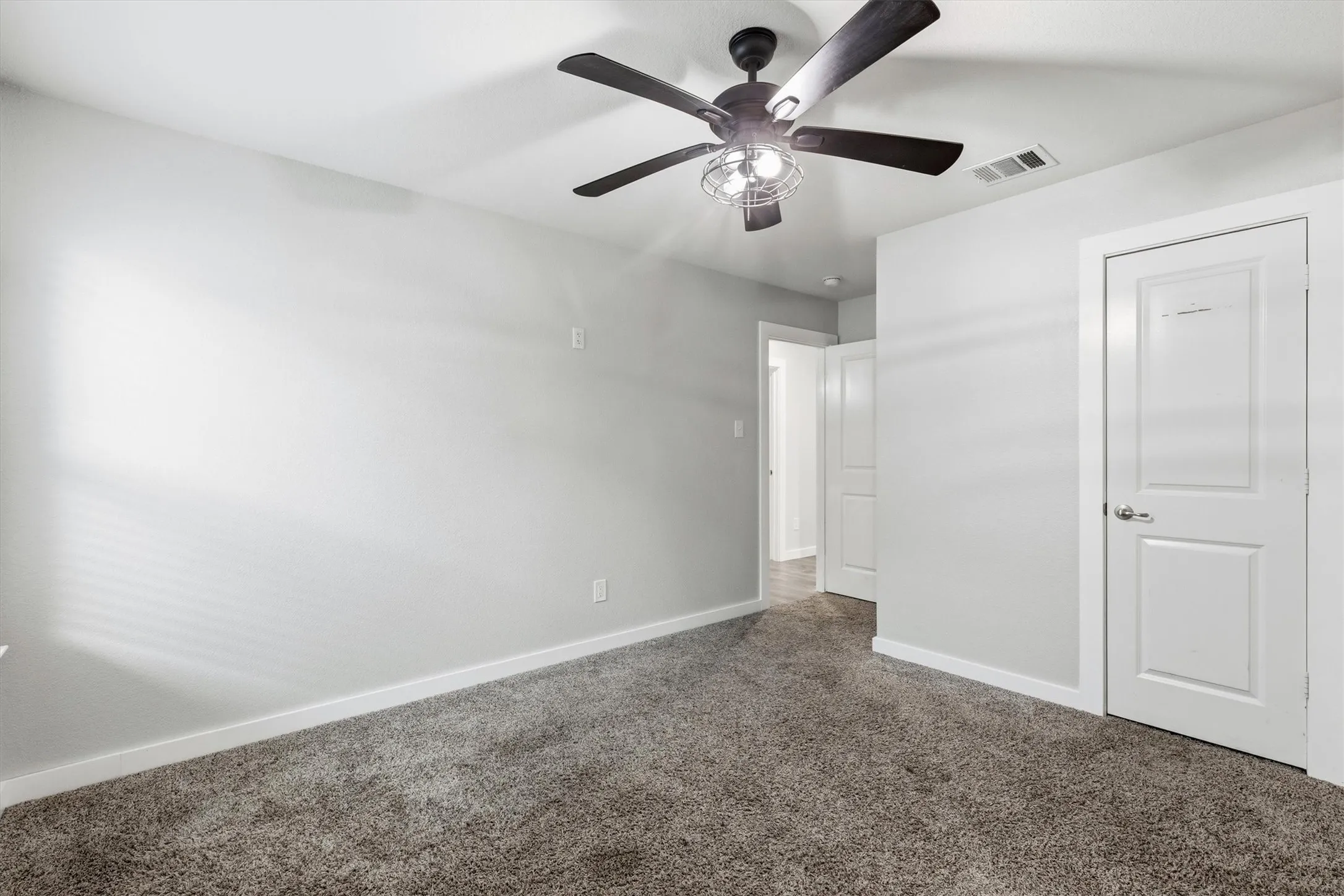 Plush carpet flooring, neutral wall tones, and a ceiling fan with integrated lighting