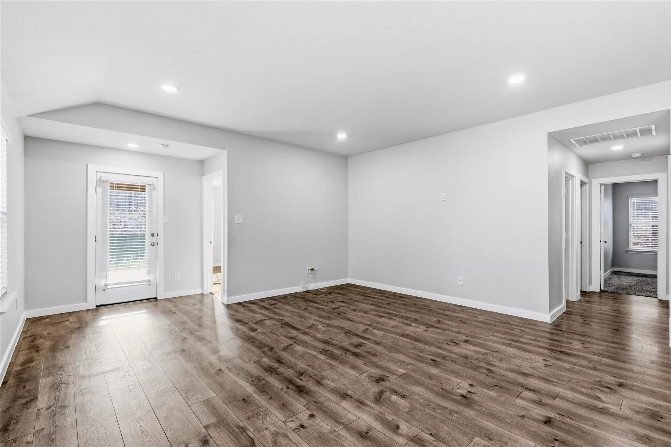 Wood-finish flooring, recessed lighting, white trim, and a glass-paneled door