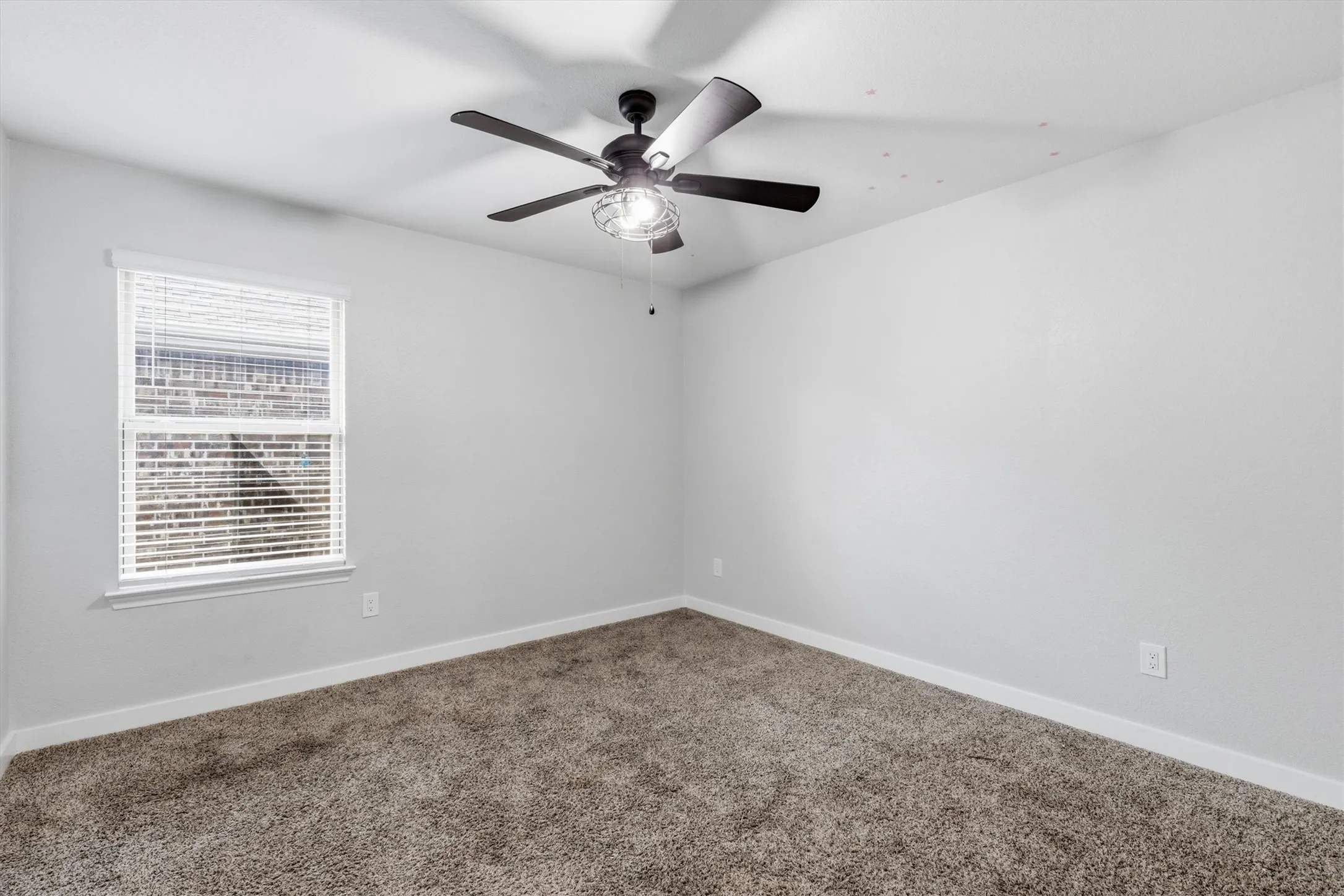 Carpeted interior with light gray walls, a window with blinds, and a ceiling fan with integrated lighting