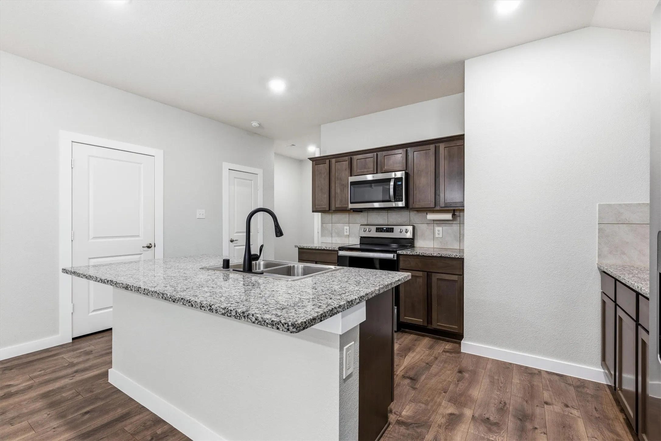 Kitchen with a central island featuring a double-basin sink and a black gooseneck faucet