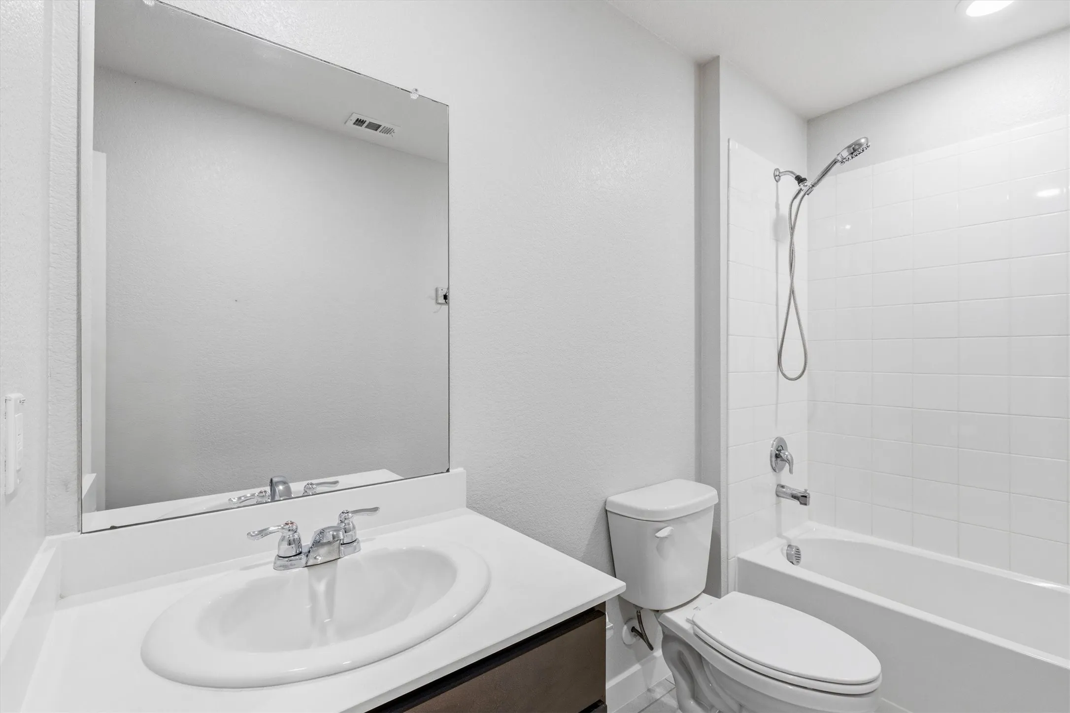 Vanity with an integrated sink, polished chrome faucet, and a large wall-mounted mirror