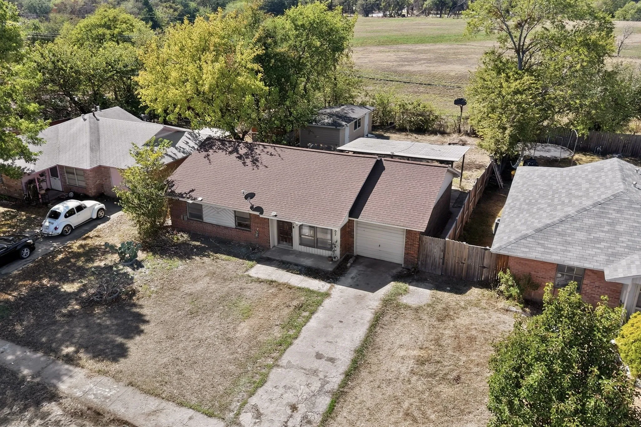 Brick exterior with a brown shingle roof, attached single-car garage, and a concrete driveway