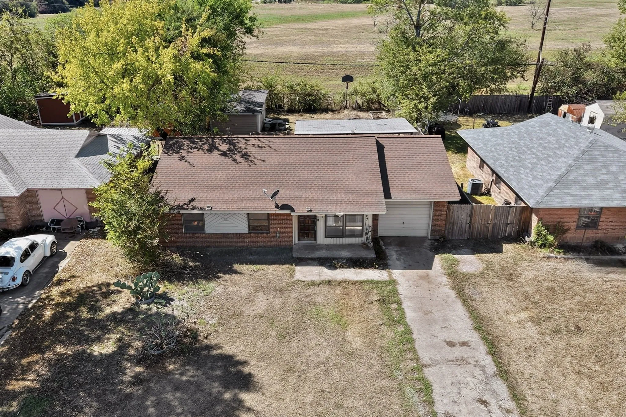 Red brick exterior with a brown shingle roof, attached garage, and concrete driveway