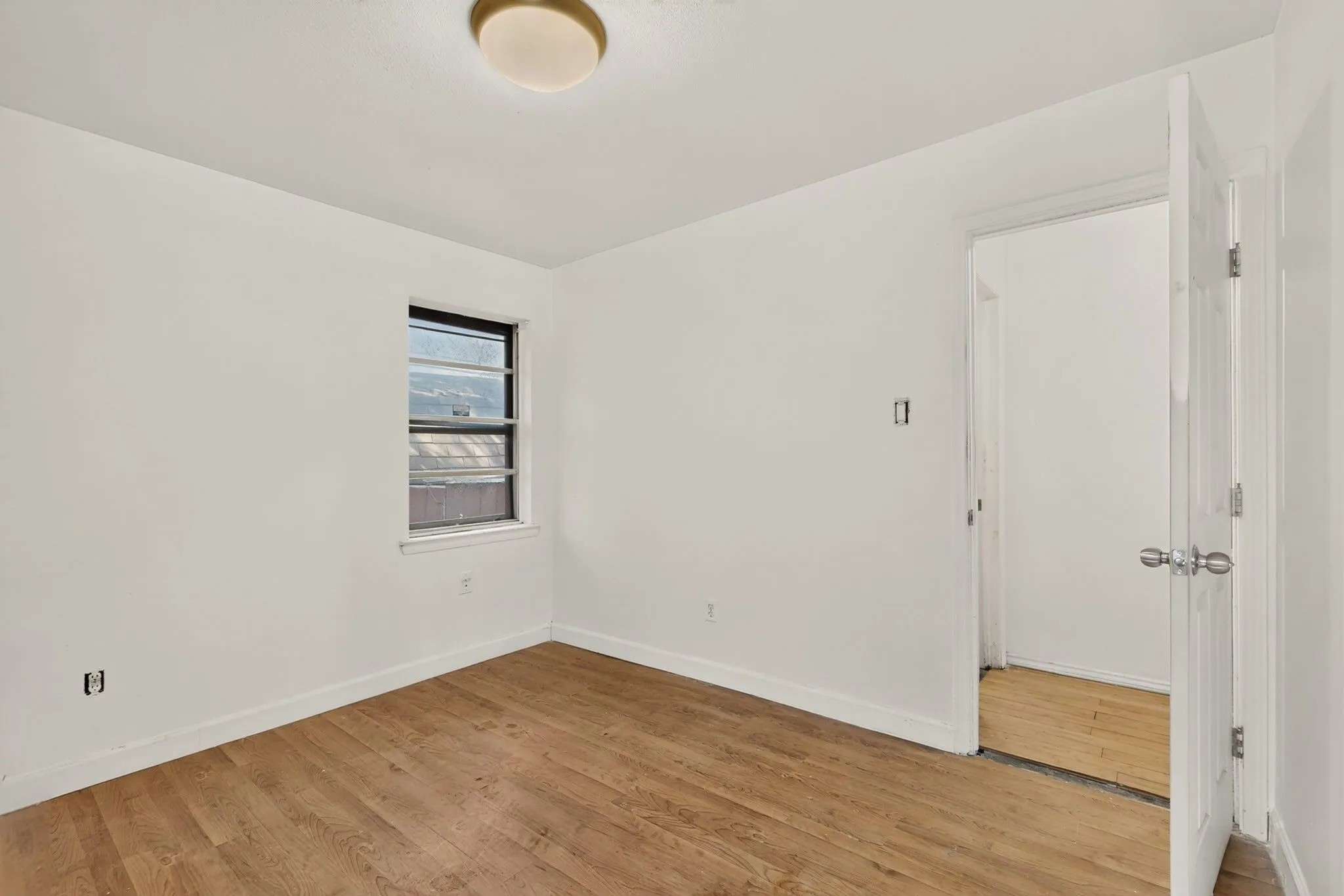 Recessed window with natural light, wood-finish flooring, and a flush-mount ceiling light fixture